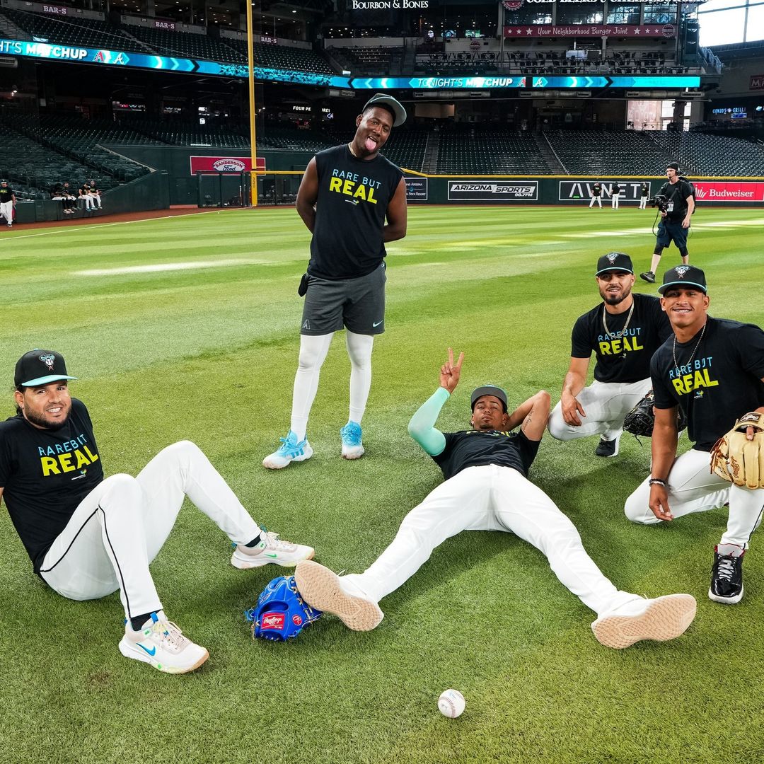 Eugenio Suarez, Geraldo Perdomo, Justin Martinez, Humberto Castellanos, and Yilber Diaz chill on the field pregame against the Atlanta Braves™ on 7/11/24 in their Rare but Real t-shirts that raise awareness for Williams syndrome.